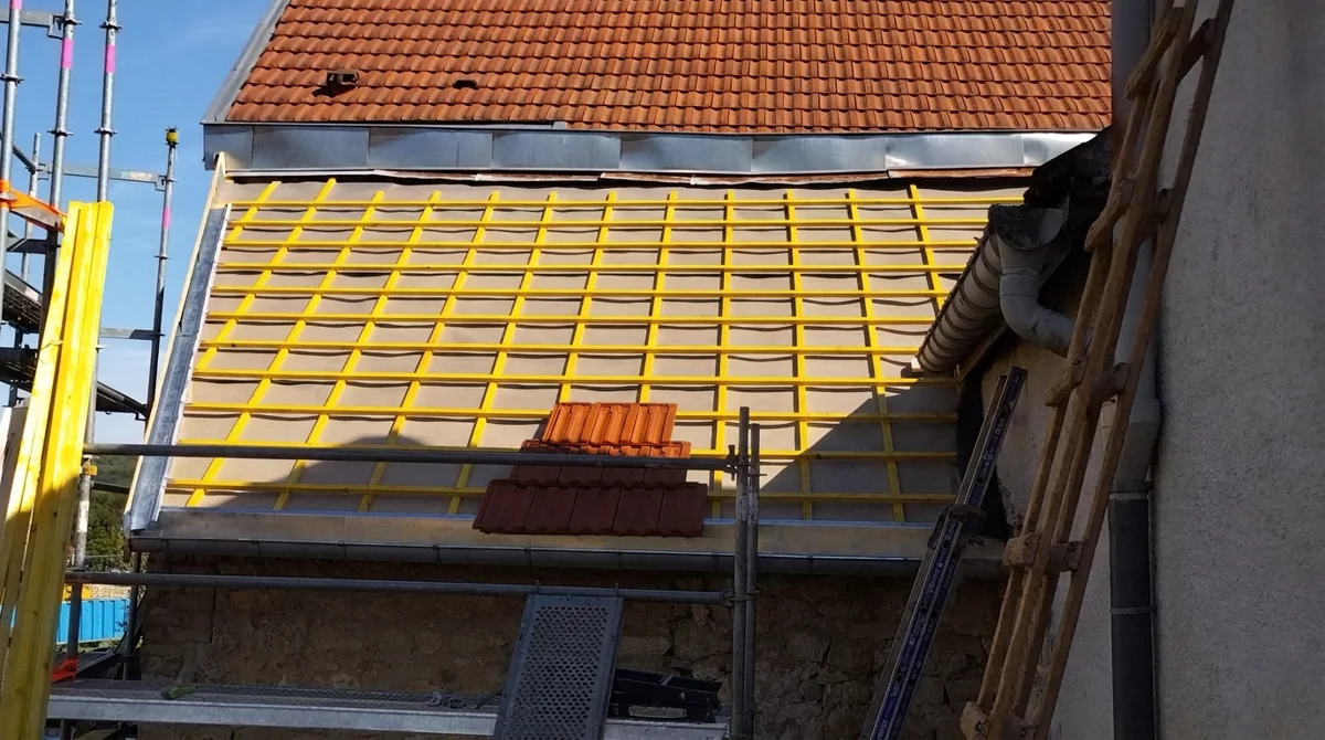 Écran de sous-toiture et liteaux jaunes pendant la rénovation
