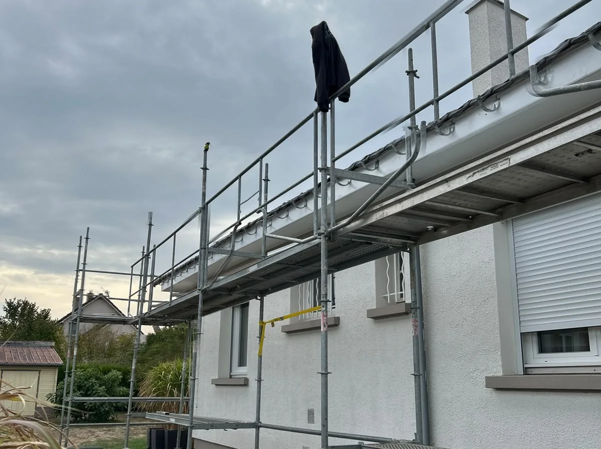 Chantier d'amélioration de toiture avec échafaudage le long d'une maison